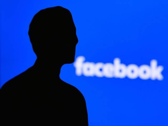 Mark Zuckerberg in front of Facebook logo